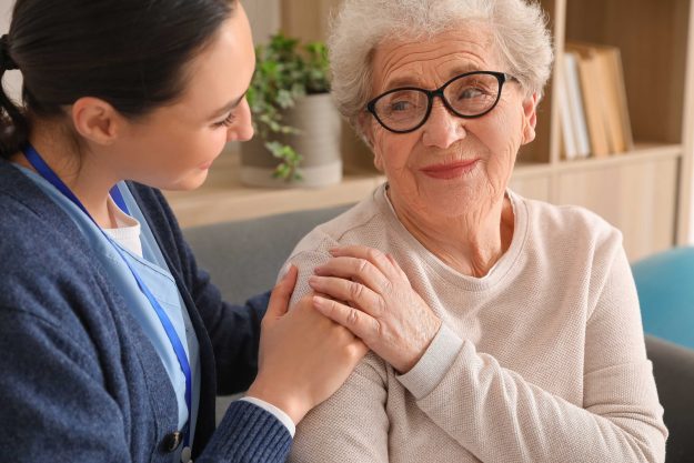 Young caregiver hugging senior woman at home, closeup Young caregiver hugging senior woman at home, closeup