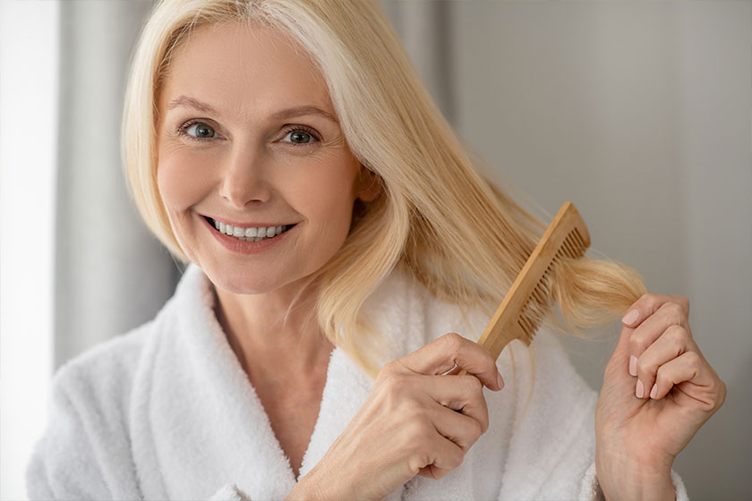 Cute blonde woman making her hair and smiling