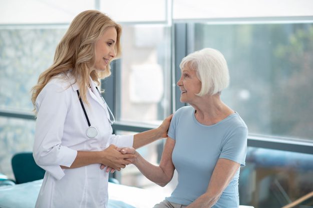 Long-haired cute smiling nurse talking to an elder Women Long-haired cute smiling nurse talking to an elder Women
