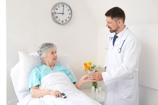 Male doctor working with elderly patient in hospital room Male doctor working with elderly patient in hospital room