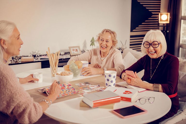 positive senior women sitting around the table