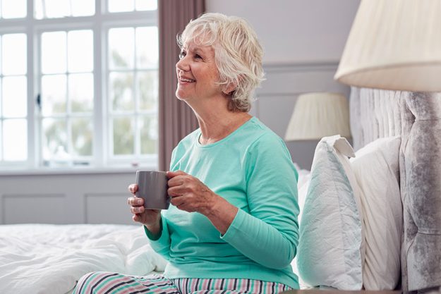 senior woman home wearing pyjamas sitting bed having morning cup senior woman home wearing pyjamas sitting bed having morning cup