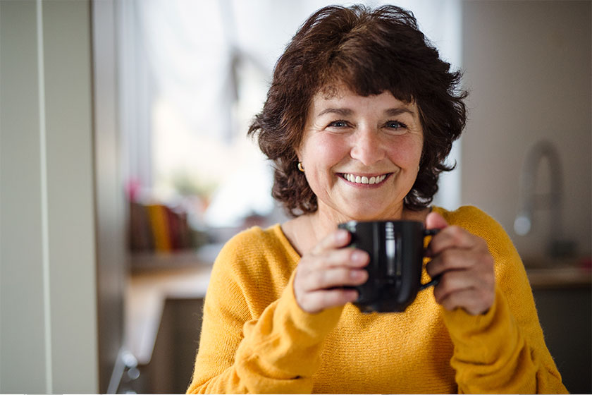 Senior woman with cup of coffee at home