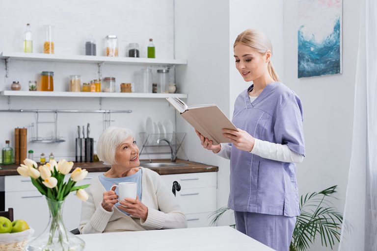 Smiling social worker reading book to aged woman Smiling social worker reading book to aged woman