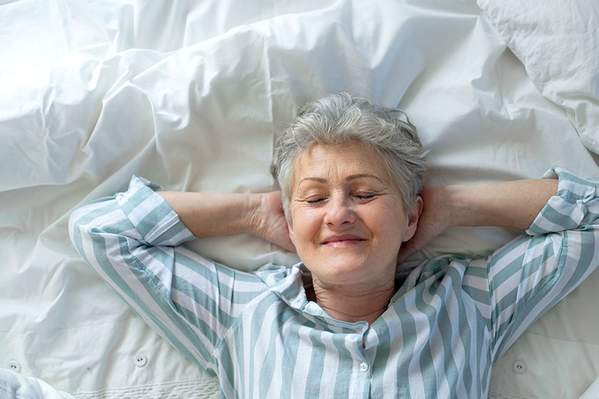 Top view of happy senior woman in bed at home