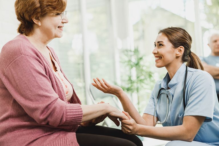young nurse senior woman holding hands while talking waiting room