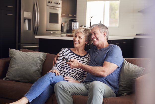 Senior white couple relaxing on couch watching television Senior white couple relaxing on couch watching television