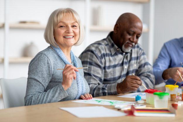Positive senior woman enjoying painting with brush Positive senior woman enjoying painting with brush