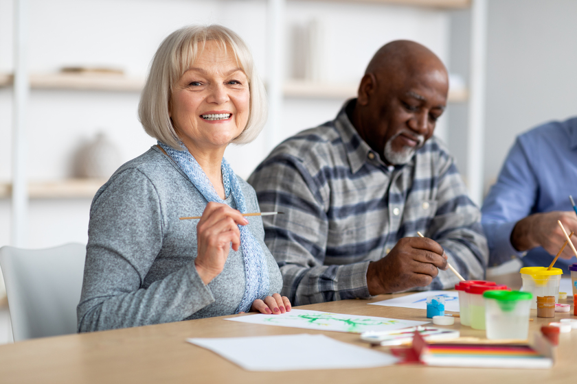 Positive senior woman enjoying painting with brush