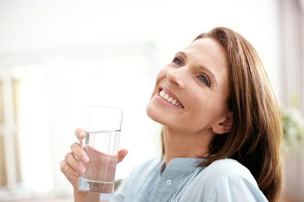 Happy thoughts and clean water. A mature woman looking pensive as she holds a glass of water. Happy thoughts and clean water. A mature woman looking pensive as she holds a glass of water.