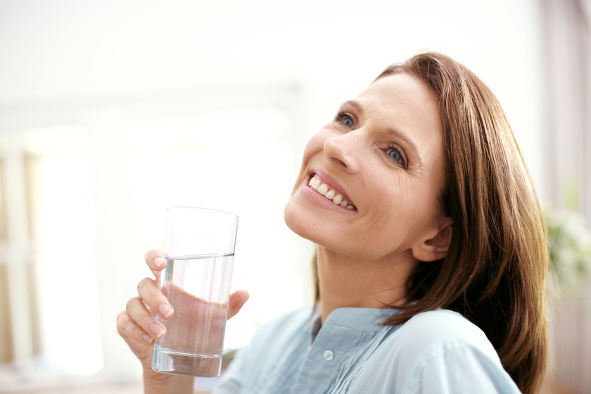 Happy thoughts and clean water. A mature woman looking pensive as she holds a glass of water. Happy thoughts and clean water. A mature woman looking pensive as she holds a glass of water.