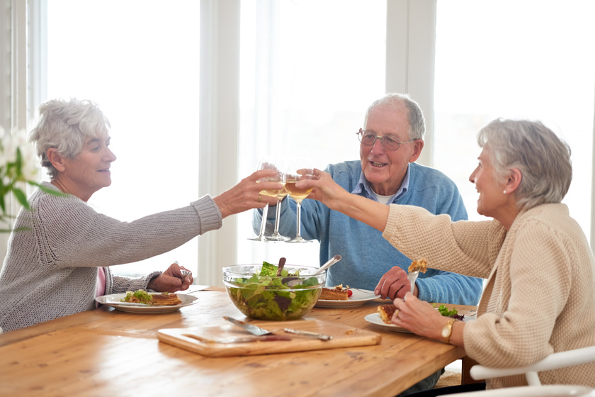 To good friends and good food. A senior man and two senior women enjoying lunch.