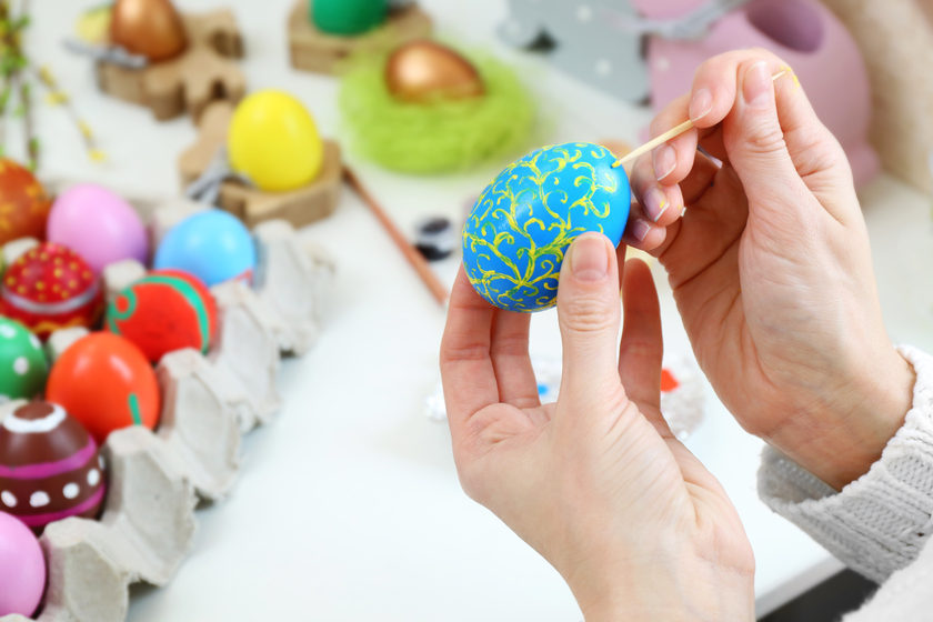 Female hands painting Easter egg at table indoors Female hands painting Easter egg at table indoors