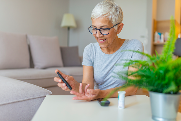 Happy mature woman with glucometer checking Happy mature woman with glucometer checking