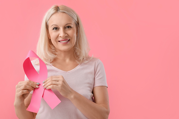 Mature woman with pink ribbon on color background.