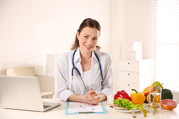 Nutritionist with clipboard and laptop at desk in office Nutritionist with clipboard and laptop at desk in office