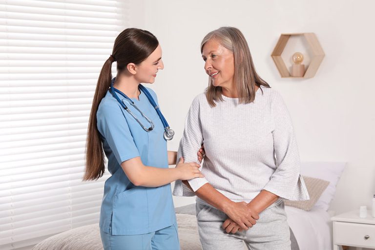 Young healthcare worker assisting senior woman indoors