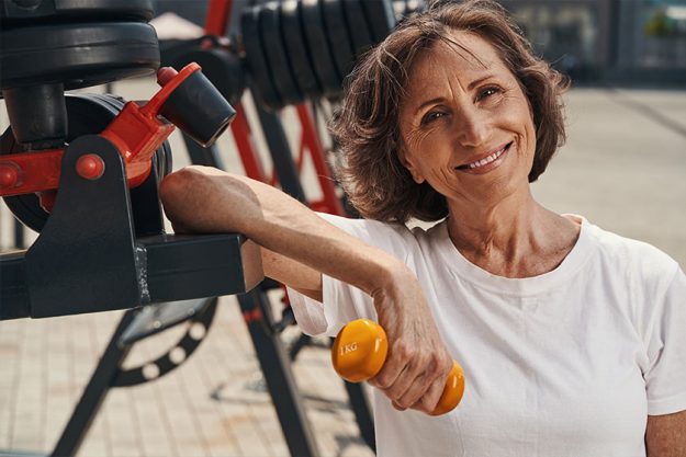 Happy aged woman spending active day on sports ground