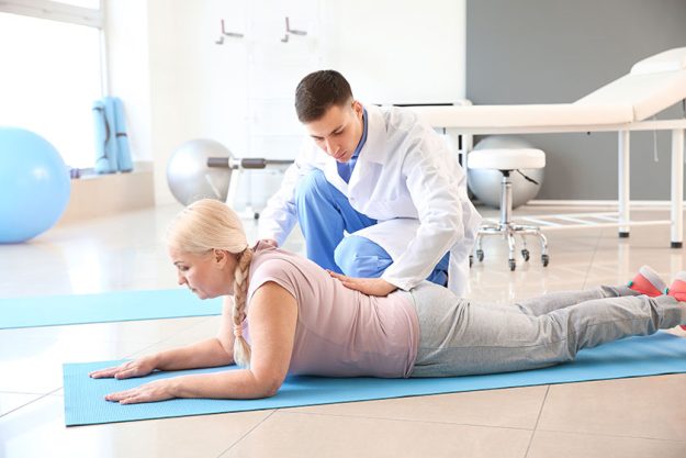physiotherapist working with mature patient in rehabilitation center