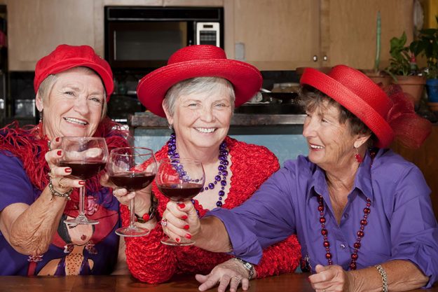 Three red hat ladies toasting with wine