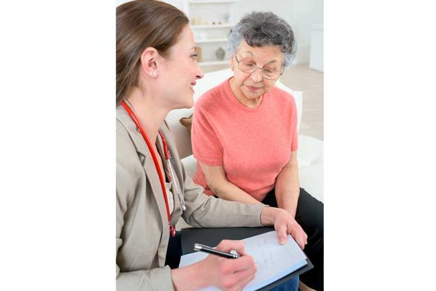doctor taking notes as she chats to senior patient