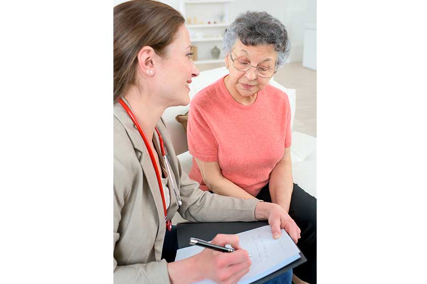 doctor taking notes as she chats to senior patient doctor taking notes as she chats to senior patient