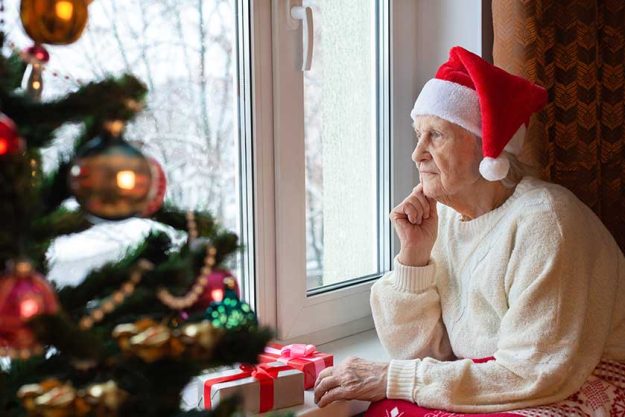 Elderly Caucasian woman wearing Santa hat sits Elderly Caucasian woman wearing Santa hat sits