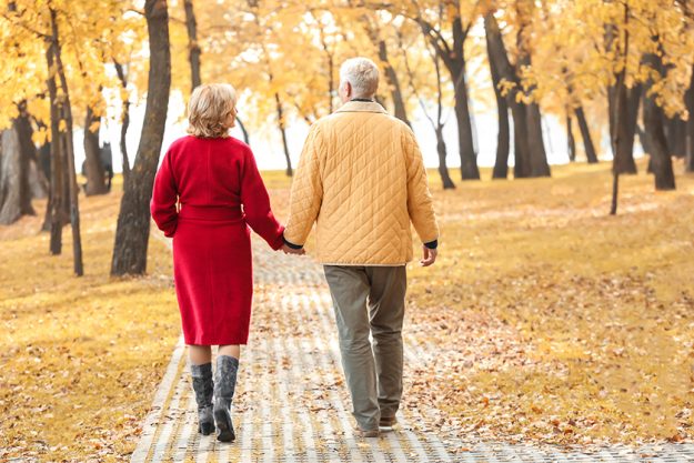 elderly couple walking in park on autumn day