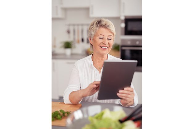happy middle aged woman with tablet at the kitchen
