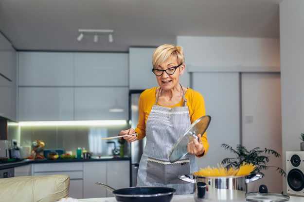 happy senior woman cooking her modern kitchen
