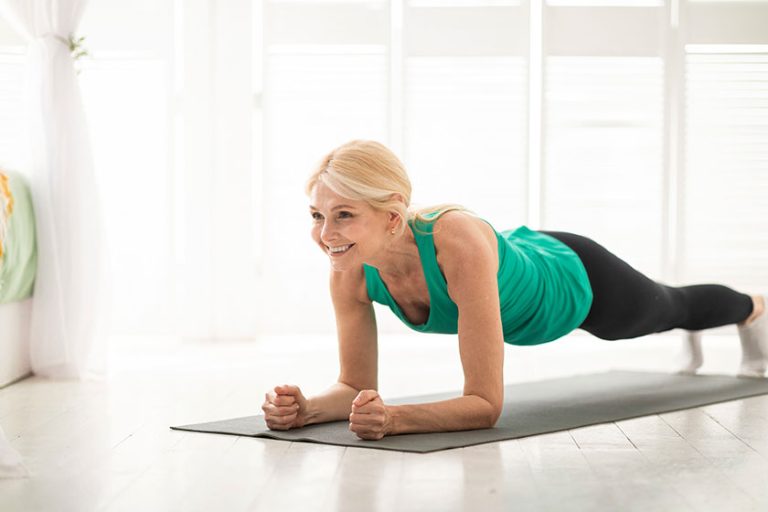 home training concept smiling senior woman doing elbow plank yoga
