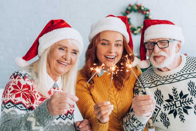 joyful senior couple daughter santa hats holding sparklers christmas