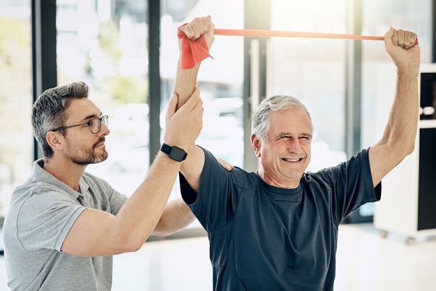 keeping his strength friendly physiotherapist helping his mature patient stretch keeping his strength friendly physiotherapist helping his mature patient stretch