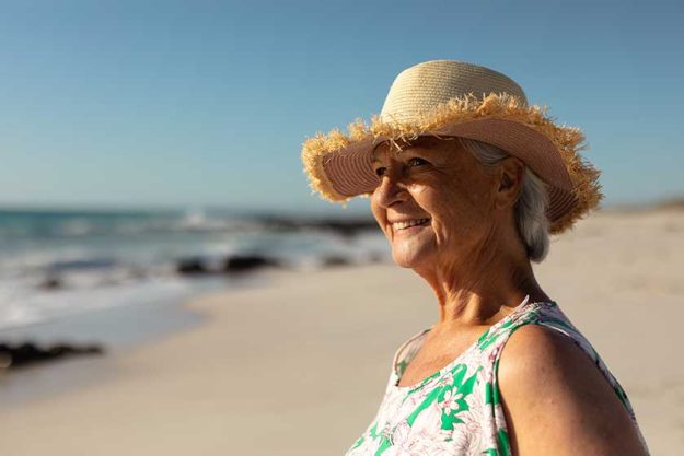 portrait senior caucasian woman beach sun wearing sun hat looking