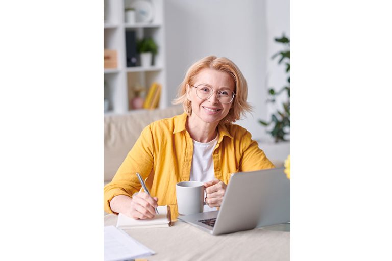 pretty smiling blond businesswoman casualwear eyeglasses looking you while working