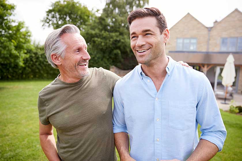 senior father adult son walking talking garden together