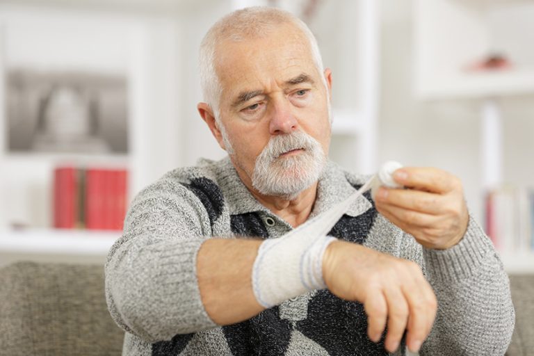 senior man doing his self bandage senior man doing his self bandage