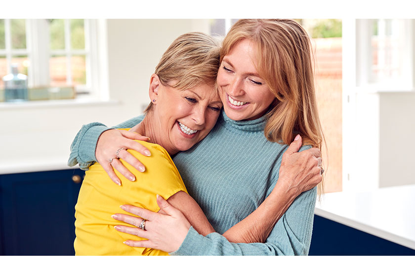 senior woman greeting hugging grown adult daughter home