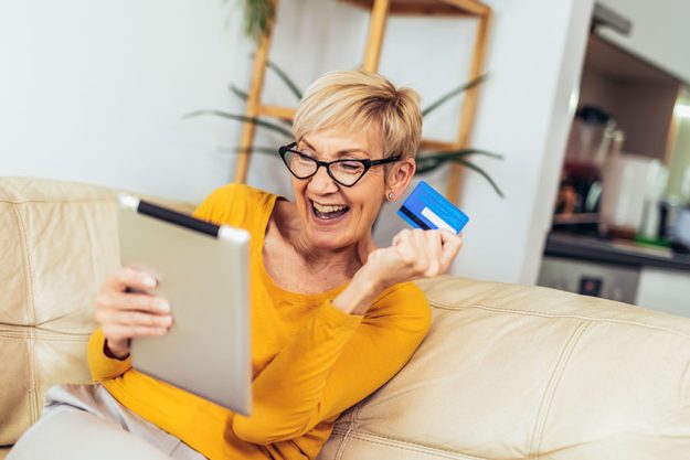 smiling mature woman shopping online credit card using digital tablet