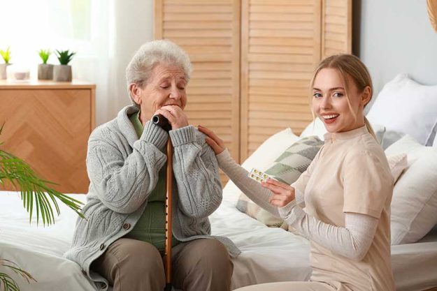 young caregiver giving pills senior woman bedroomc