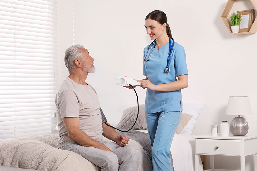 young healthcare worker measuring senior man blood pressure indoors