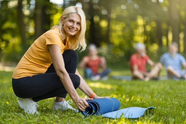 Happy Beautiful Mature Lady Rolling Yoga Mat After Sport Training Outdoors Happy Beautiful Mature Lady Rolling Yoga Mat After Sport Training Outdoors