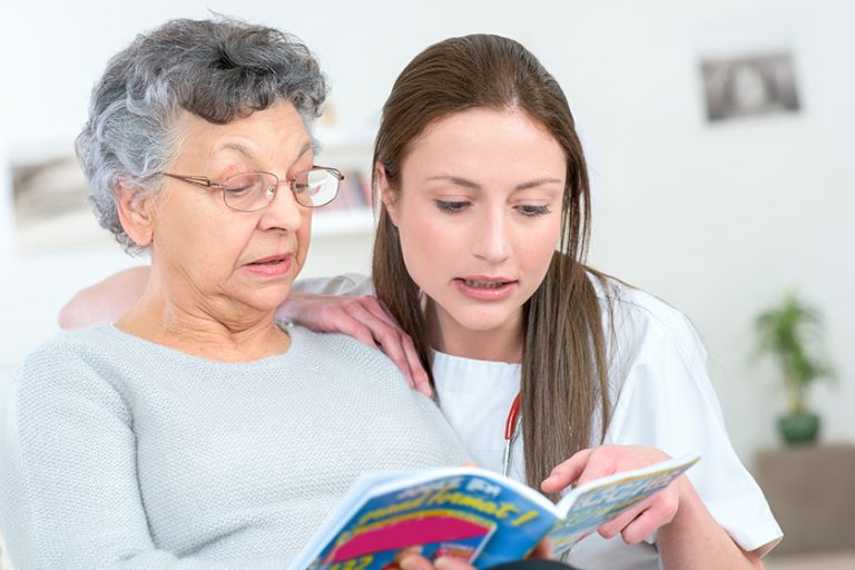 caregiver reading a book with an elderly patient