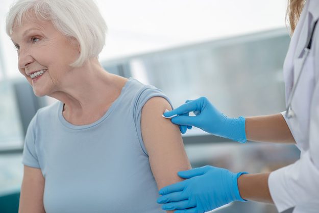 nurse making an injection to an elderly smiling woman