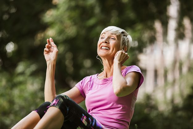 senior woman exercising park while listening music senior woman exercising park while listening music