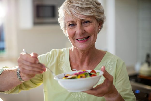 senior woman holding vegetable salad in bowl
