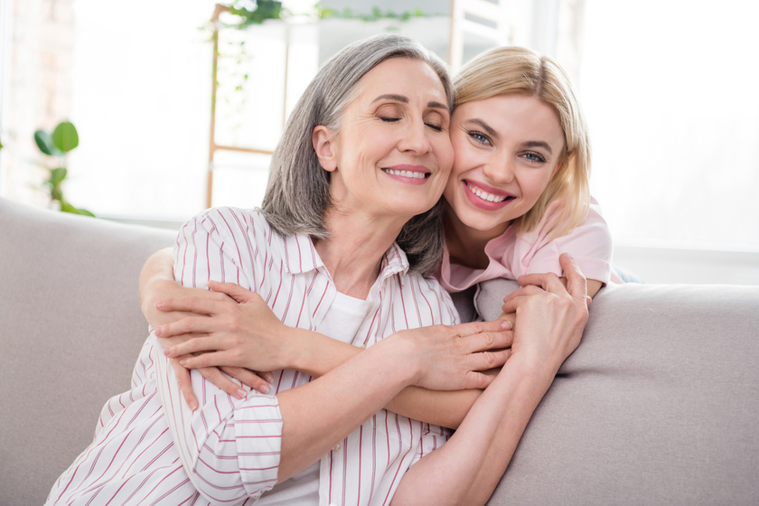 Portrait of two attractive sweet dreamy cheerful women granddaughter hugging granny at home indoor