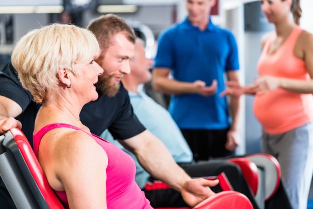 senior woman in group with pregnant woman working out at the gym senior woman in group with pregnant woman working out at the gym