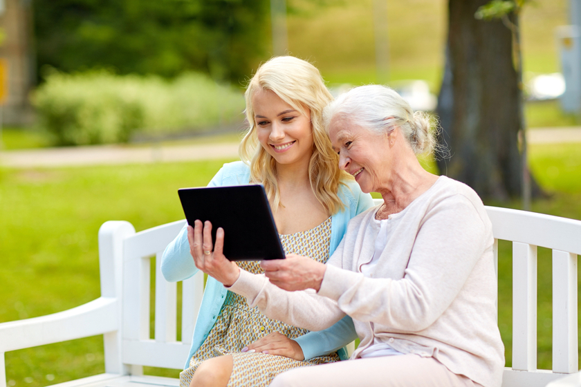 daughter and senior mother with tablet pc at park daughter and senior mother with tablet pc at park