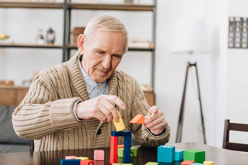 Retired man playing wooden toys home Retired man playing wooden toys home